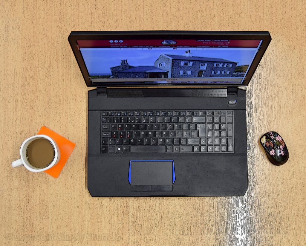 Overhead shot of laptop on desk with Simply Shutters website on screen. 