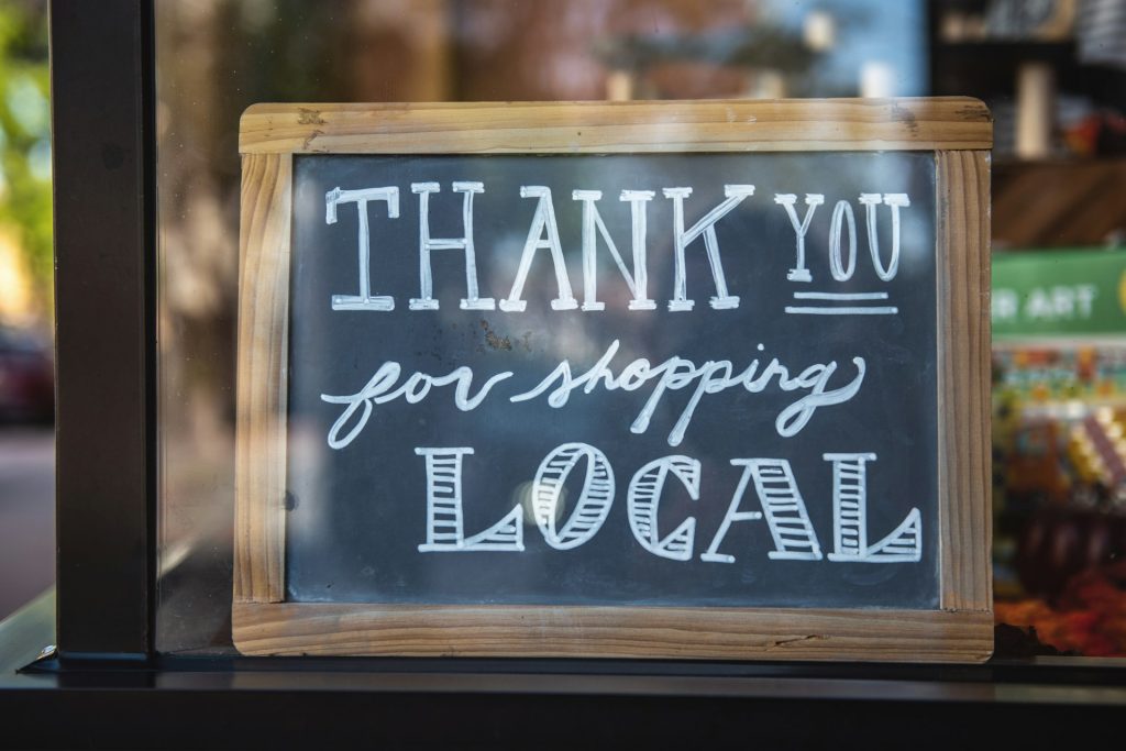 Close up of chalkboard sign in shop window that reads thank you for shopping local. 